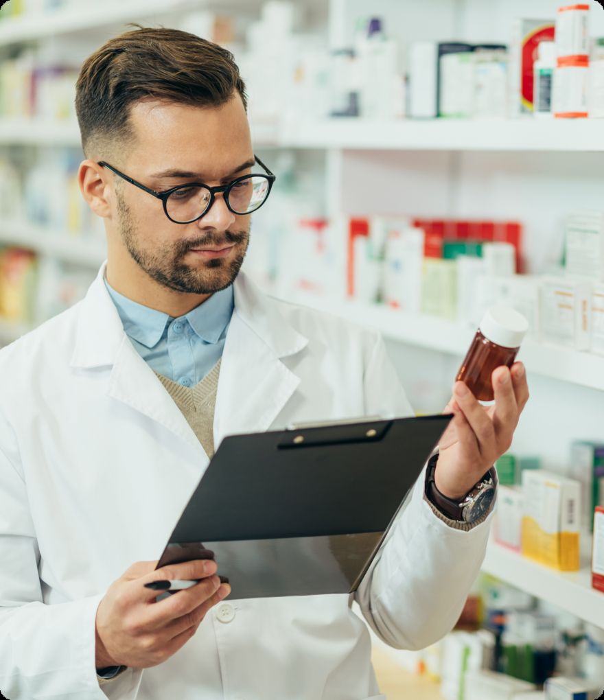 A pharmacist checking a prescription and inspecting a medicine bottle in a pharmacy
